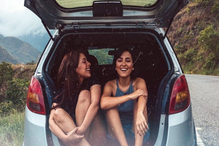 Laughing girls at the car's rear compartment.