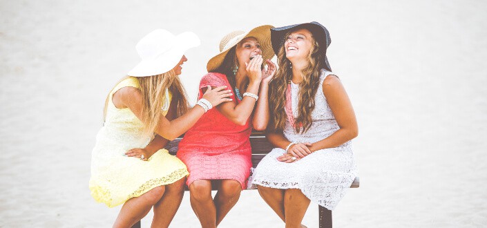 Three girls sitting on a bench, share and laugh at corny jokes.