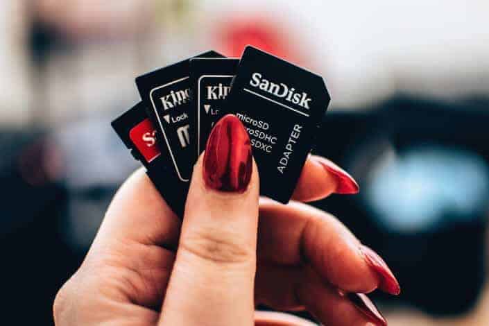 Four memory cards held by a nail-polished fingers. 