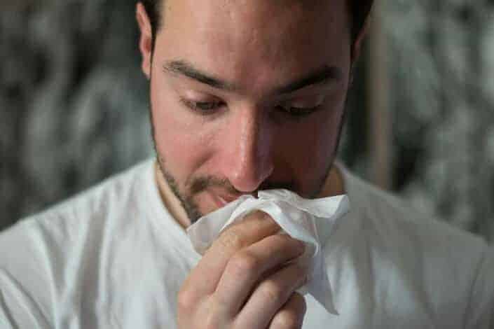 Sneezing man covers his nose with a napkin.