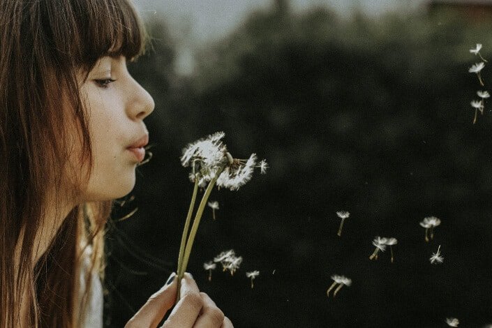 A girl blowing the dandelion flower.