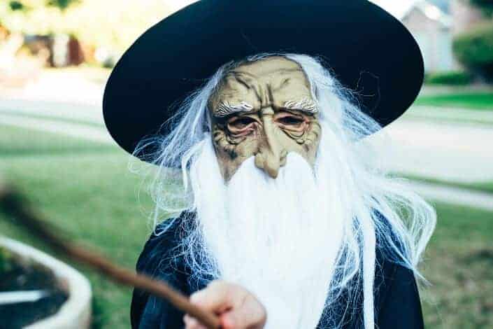 Person in an elf-wizard mask pointing a magic wand.