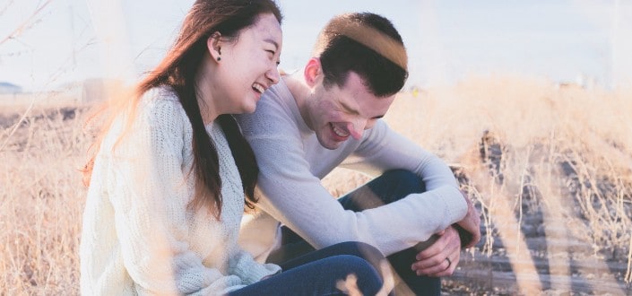 Couple laughing while sitting on the field