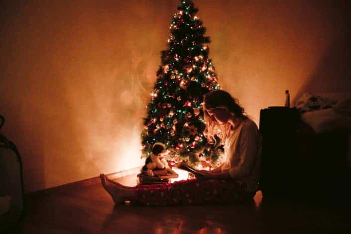 Woman sitting beside a christmas tree