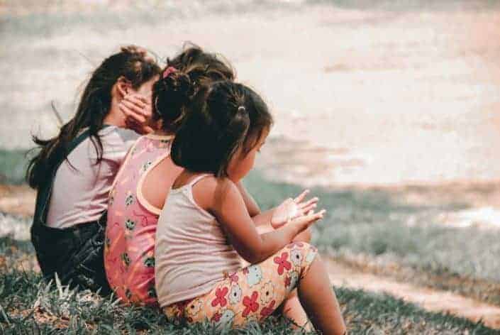 Three little girls sitting on the grass.