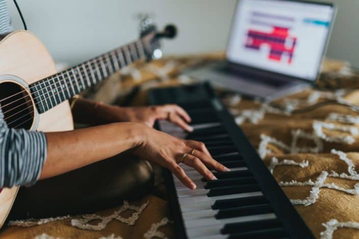 woman with a guitar has her hands on a piano